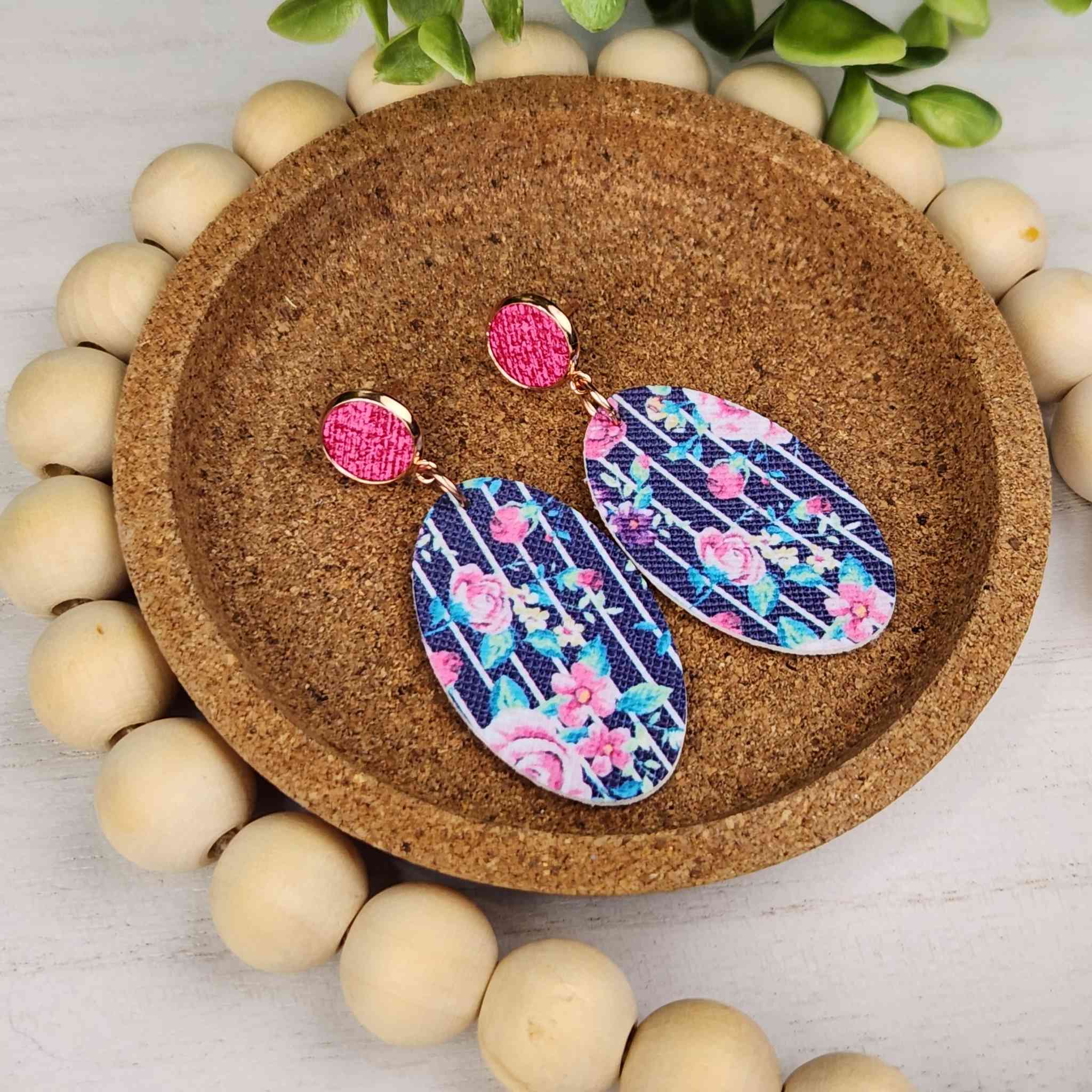 Pink studs with a dange that is 40mm long. The dangle is faux leather and has a blue and pink floral pattern 