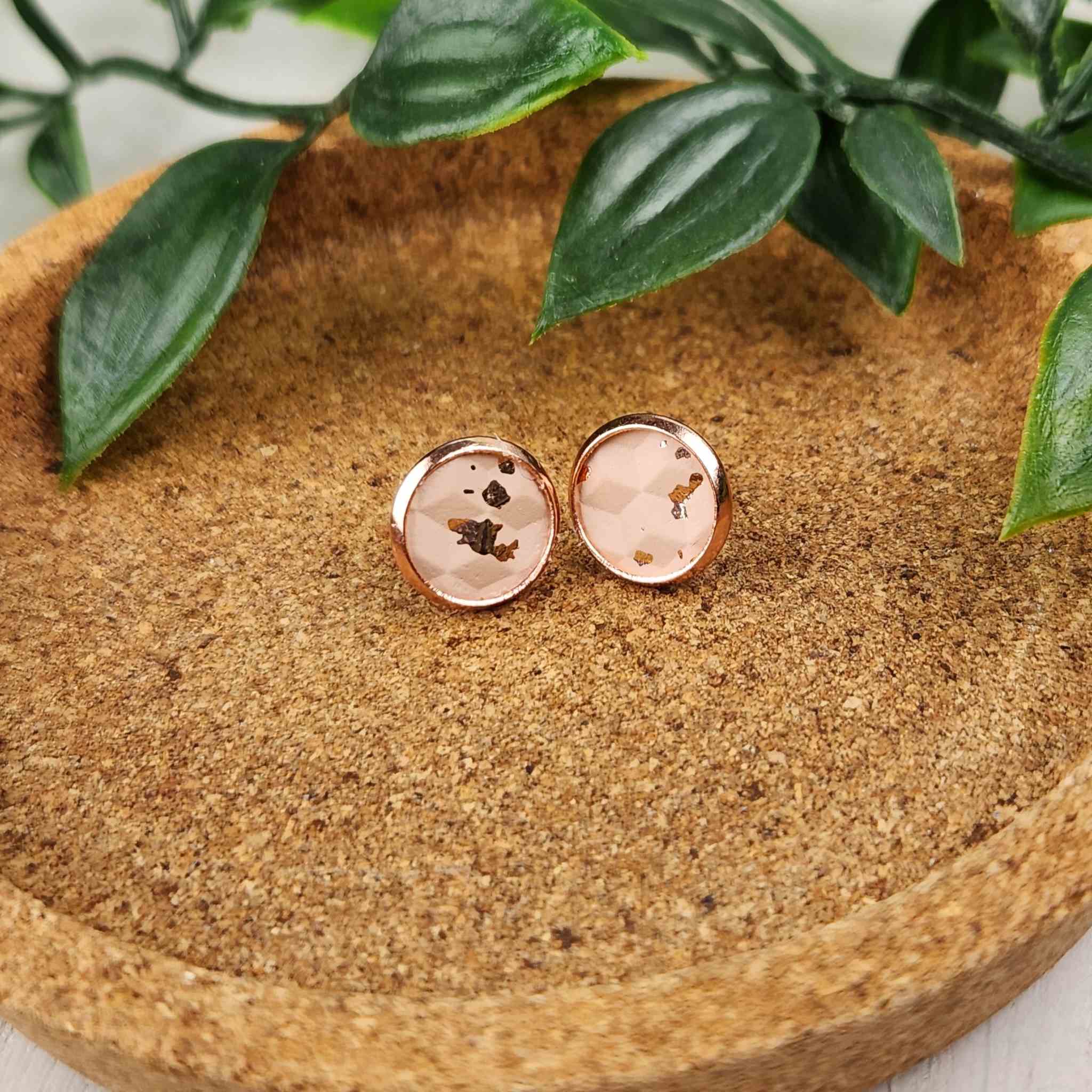 Hypoallergenic rose gold studs with faux leather inlay. Inlay is a speckled, salmon colored pattern. Studs are 10mm in diameter.