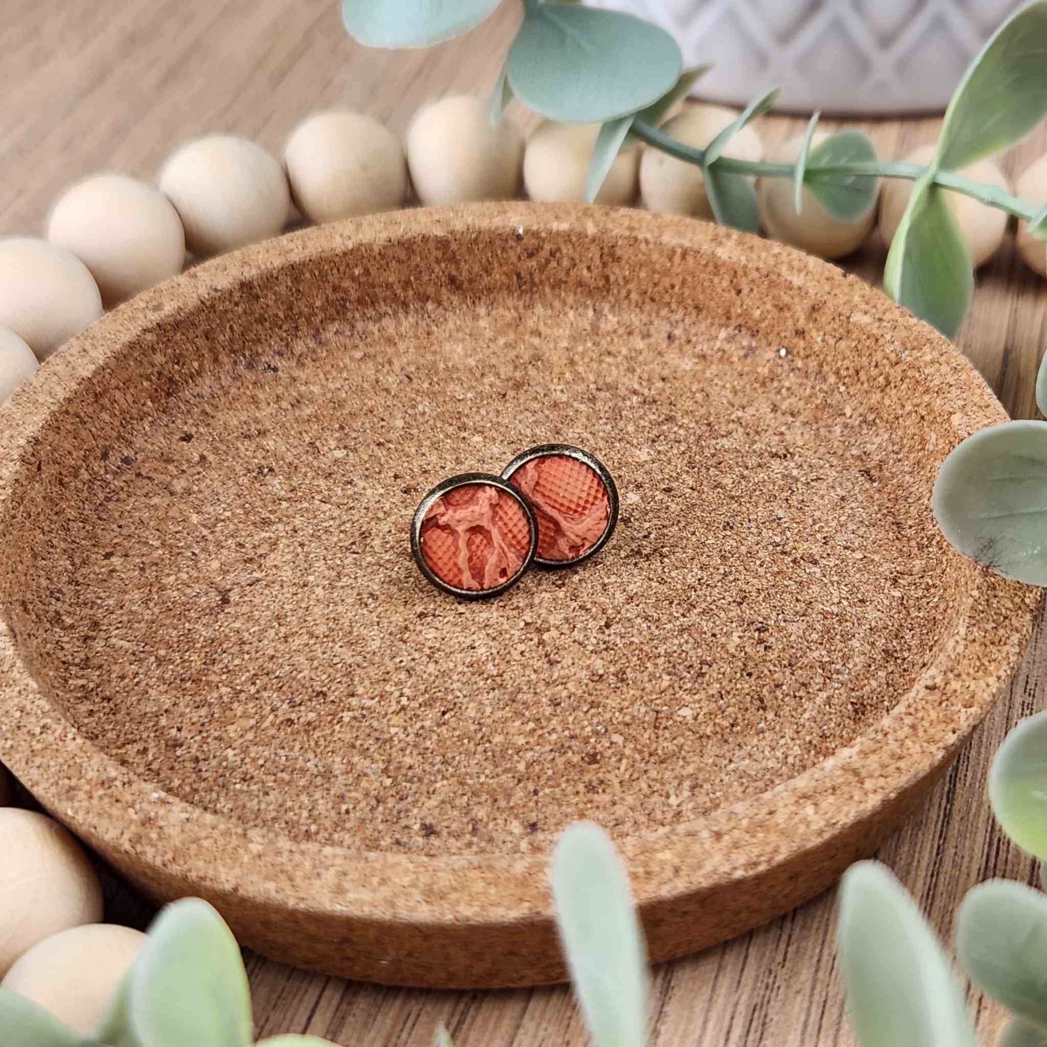 A pair of rustic orange colored studs. Made with a faux leather inlay and hypoallergenic findings. These studs are 10mm in diameter.