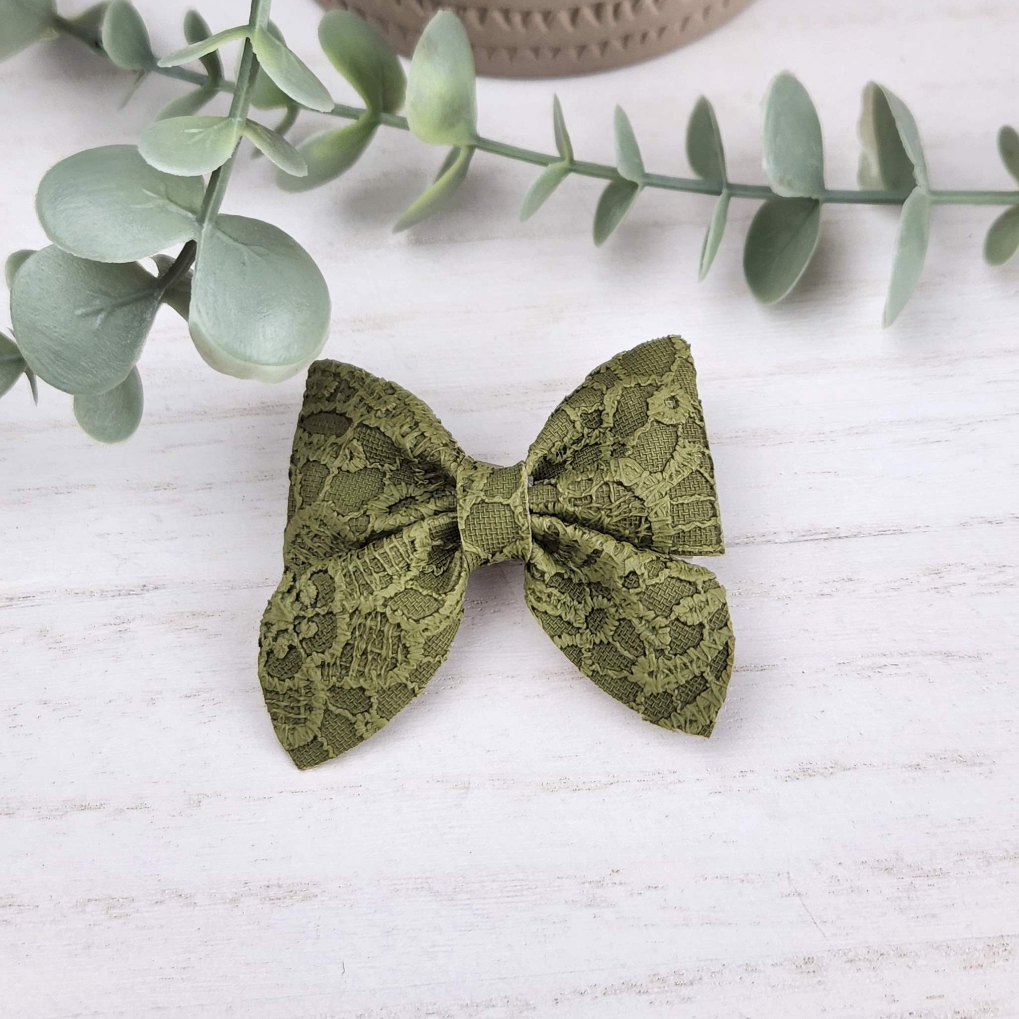 Green sailor bow made with faux leather, has an alligator clip to fasten to hair.