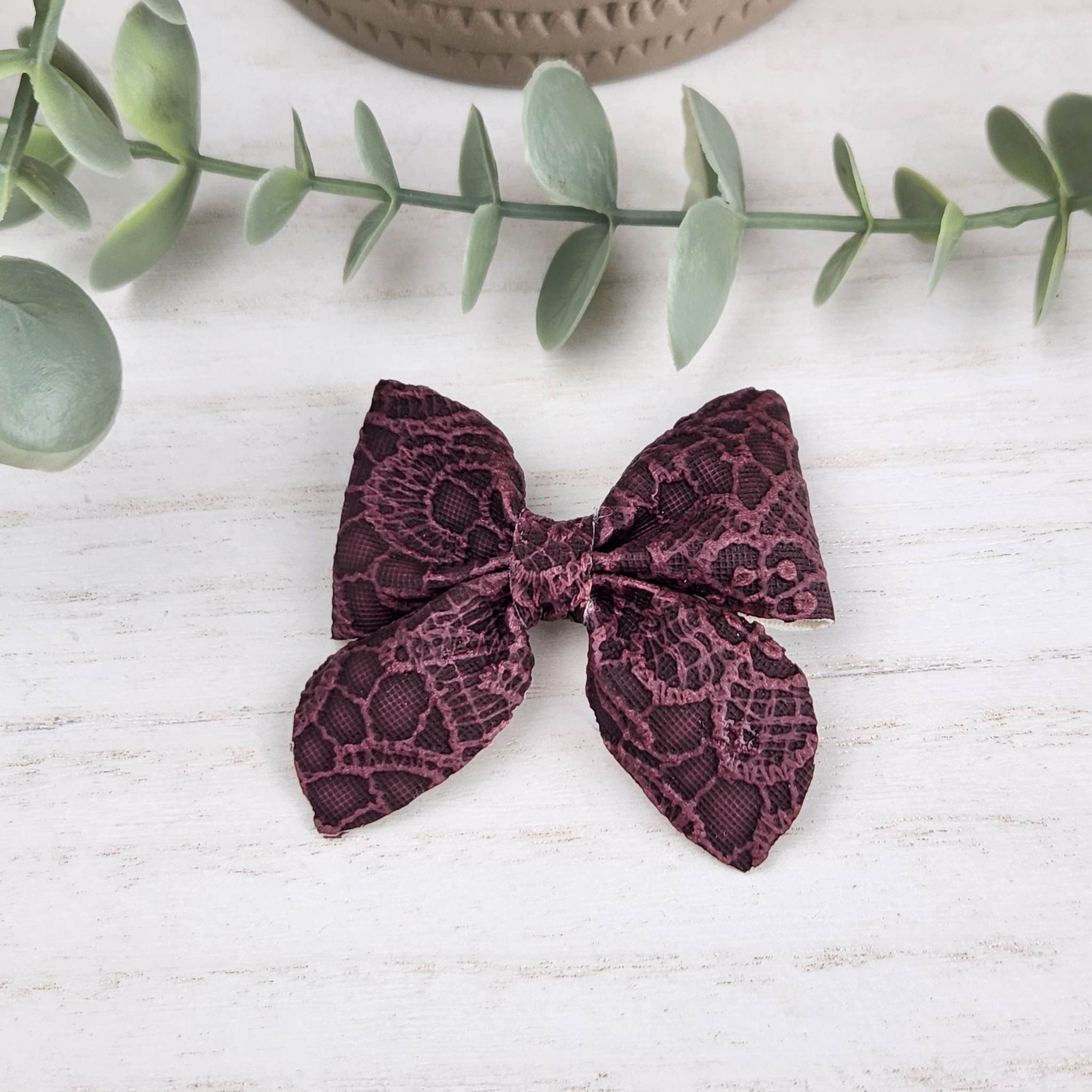 Purple sailor bow made with faux leather, has an alligator clip to fasten to hair.