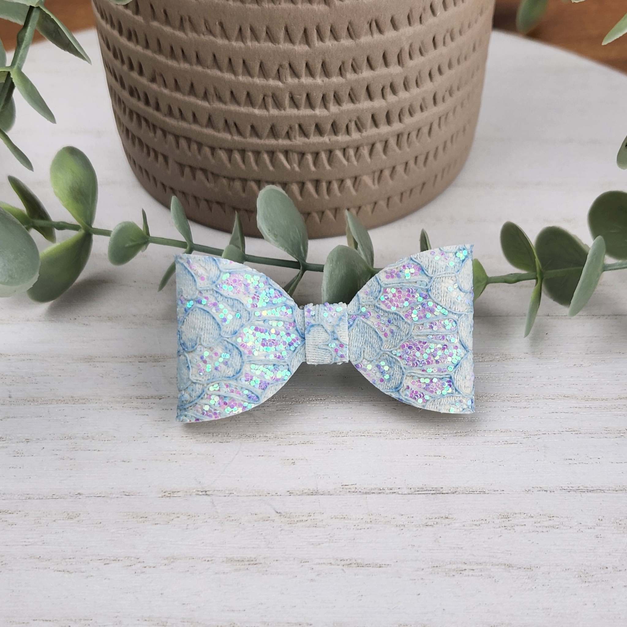 Blue glitter classic bow made with faux leather, has an alligator clip to fasten to hair.