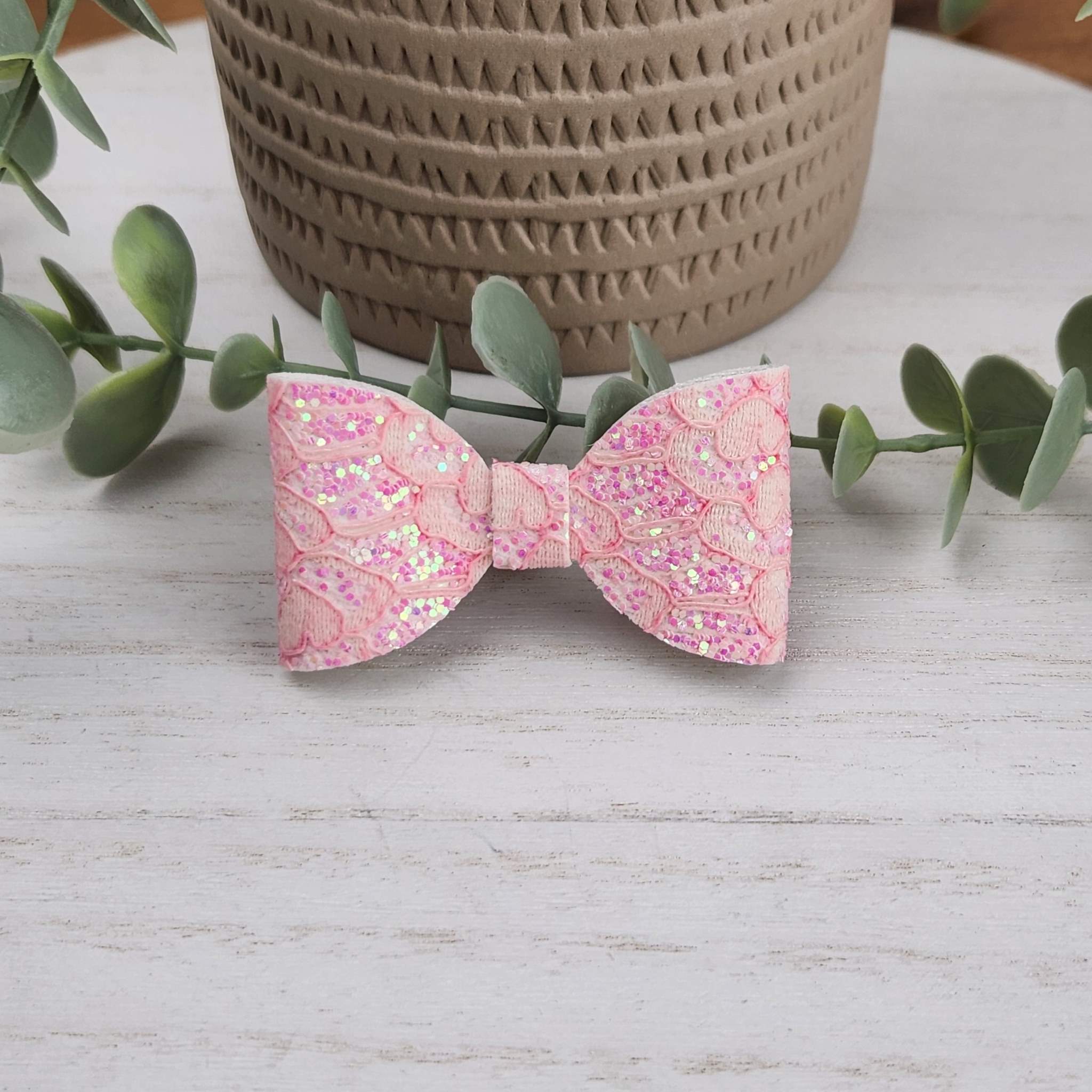 Pink glitter classic bow made with faux leather, has an alligator clip to fasten to hair.