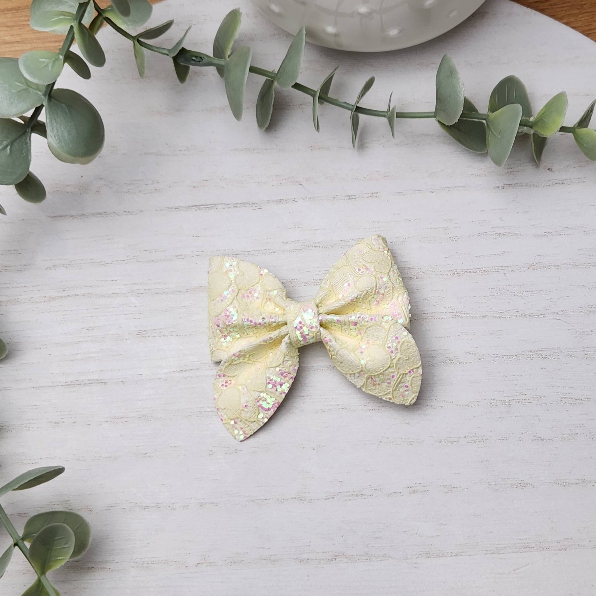 Yellow glitter sailor bow made with faux leather, has an alligator clip to fasten to hair.