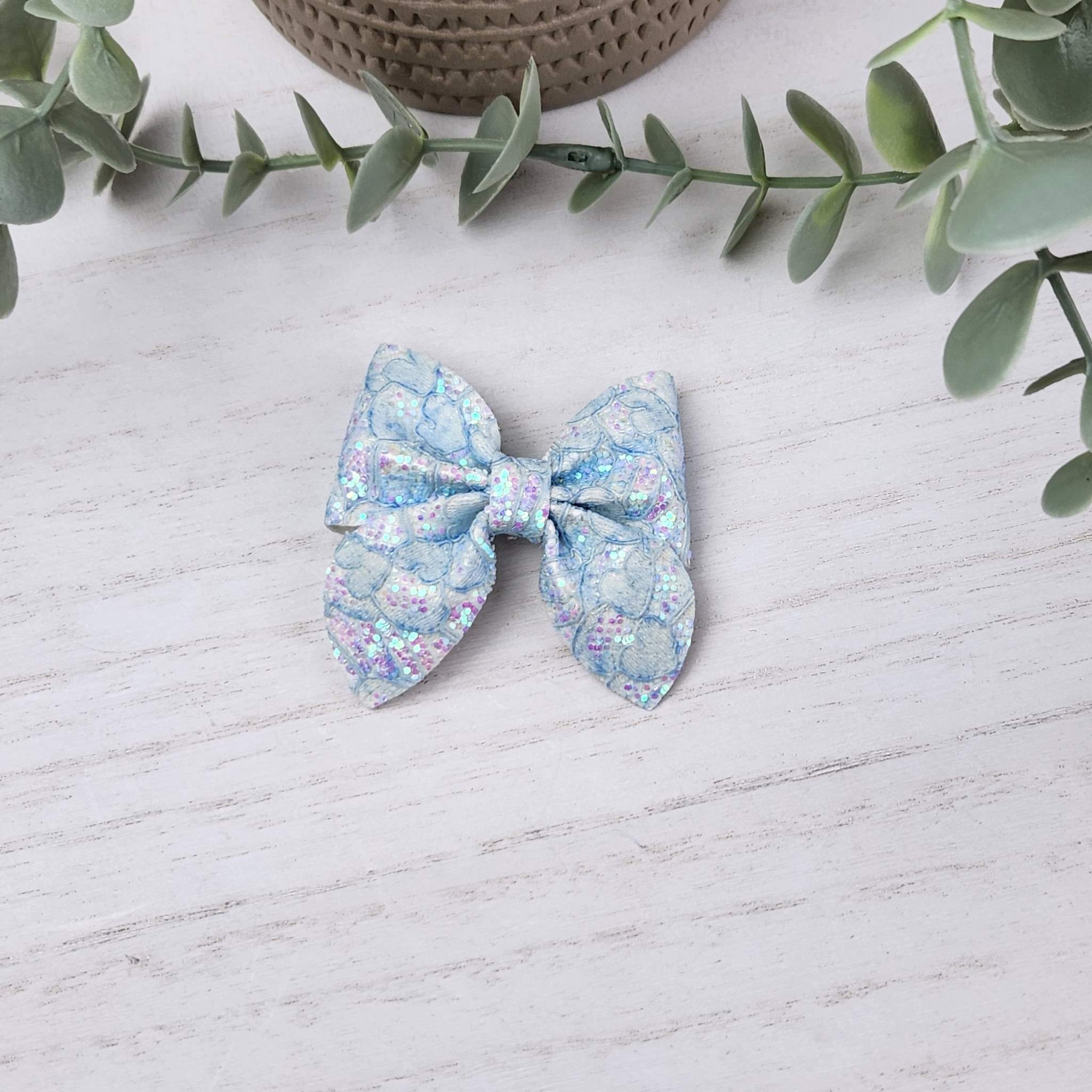 Blue glitter sailor bow made with faux leather, has an alligator clip to fasten to hair.