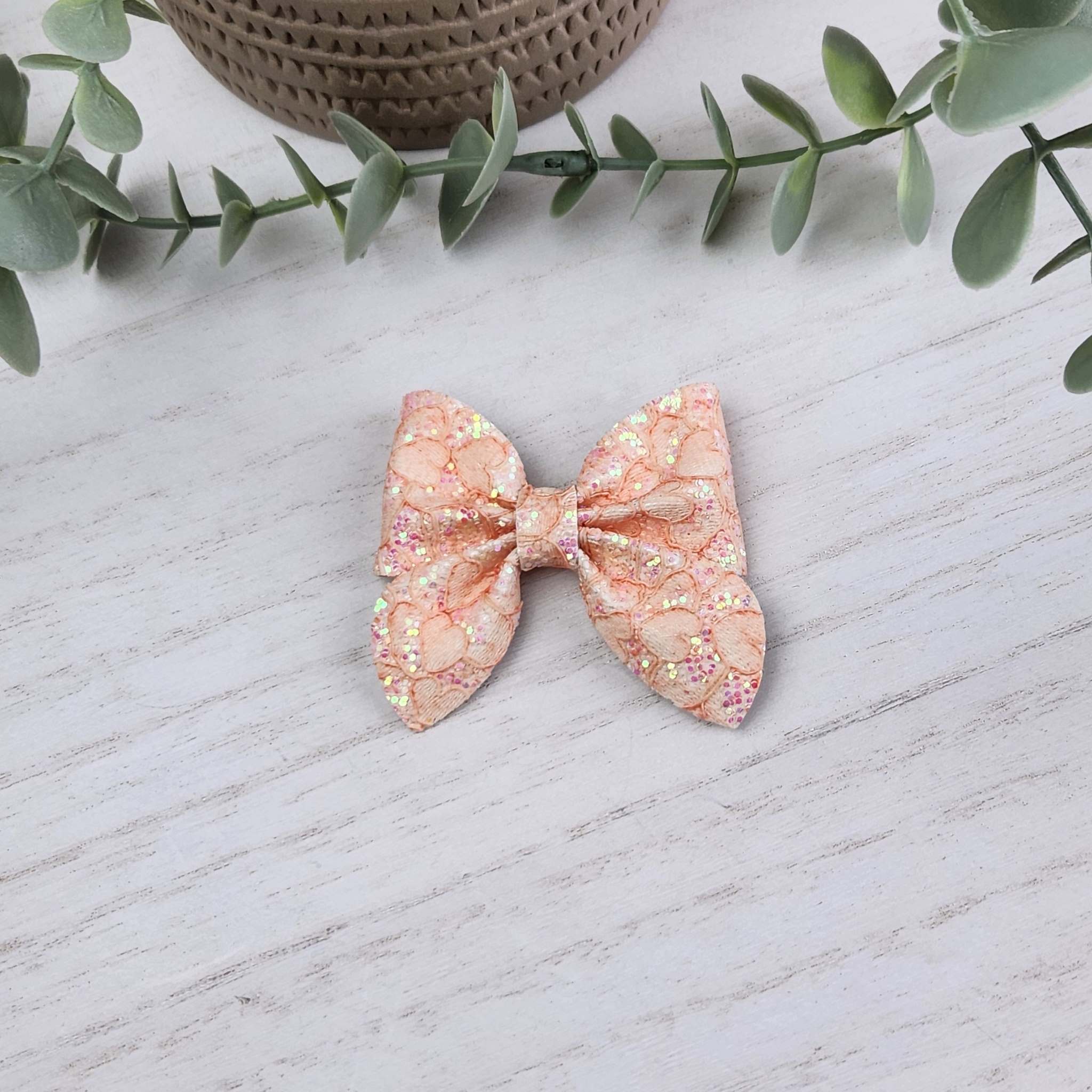 Coral glitter sailor bow made with faux leather, has an alligator clip to fasten to hair.