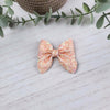 Coral glitter sailor bow made with faux leather, has an alligator clip to fasten to hair.