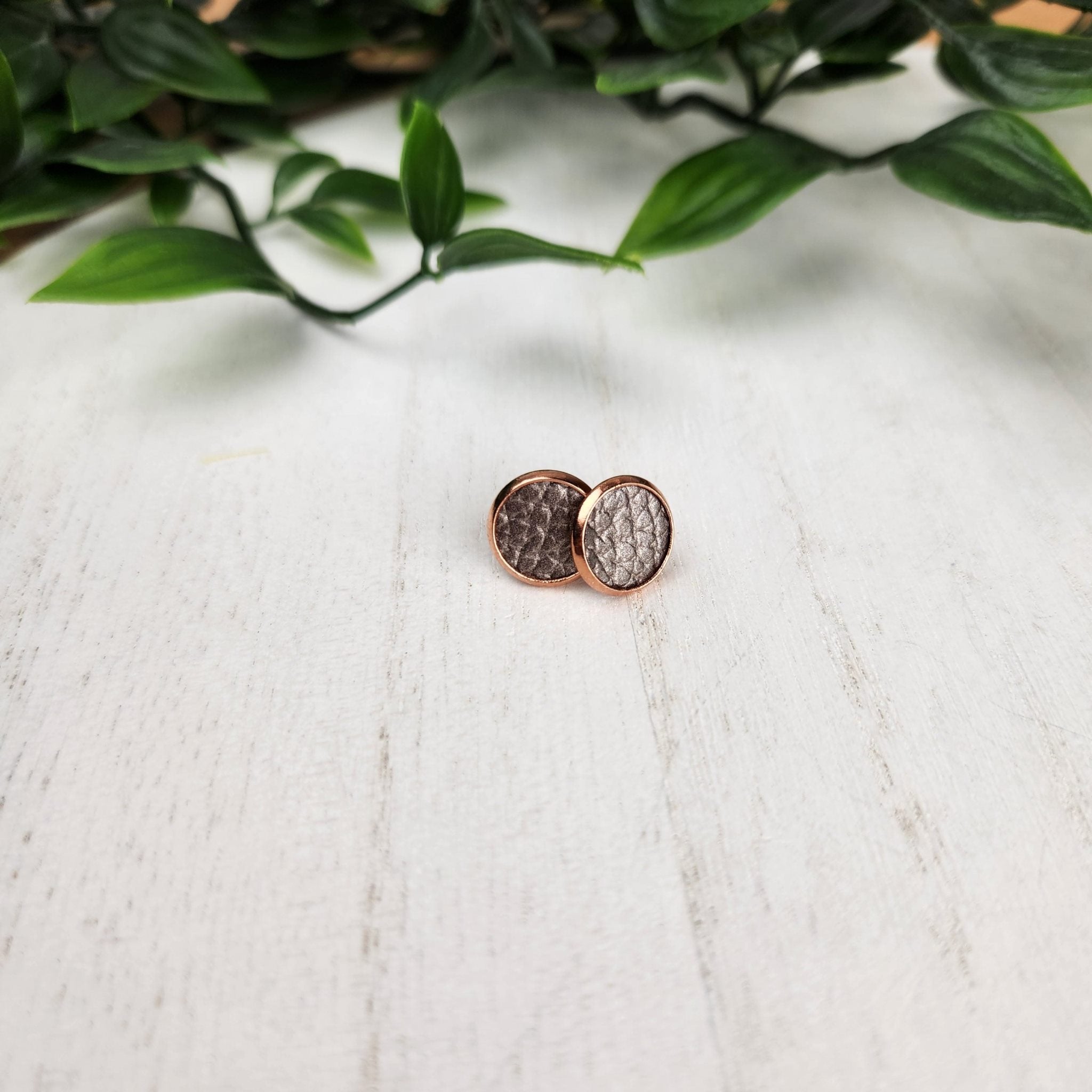 Cute pair of pearlescent grey studs. Made with faux leather inlay and hypoallergenic gold plated studs. The studs are 10mm in diameter.