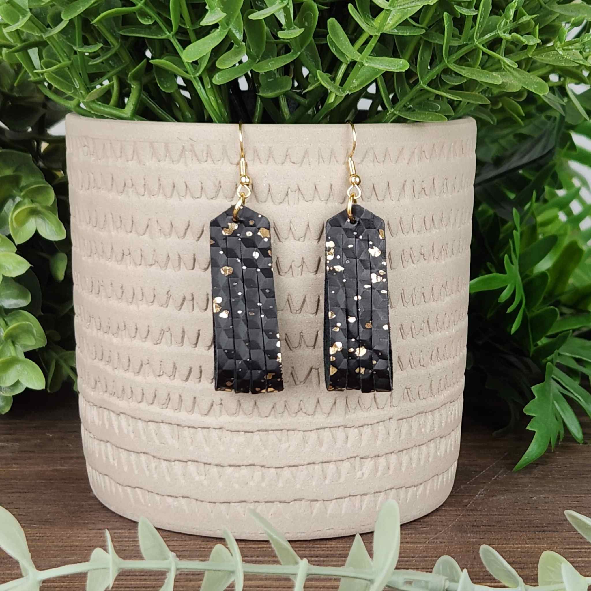 A gold speckled black faux leather earring. Has a gold plated ring above the leather.