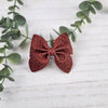 Red sailor bow made with faux leather, has an alligator clip to fasten to hair.