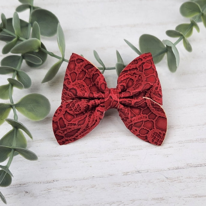 Red sailor bow made with faux leather, has an alligator clip to fasten to hair.