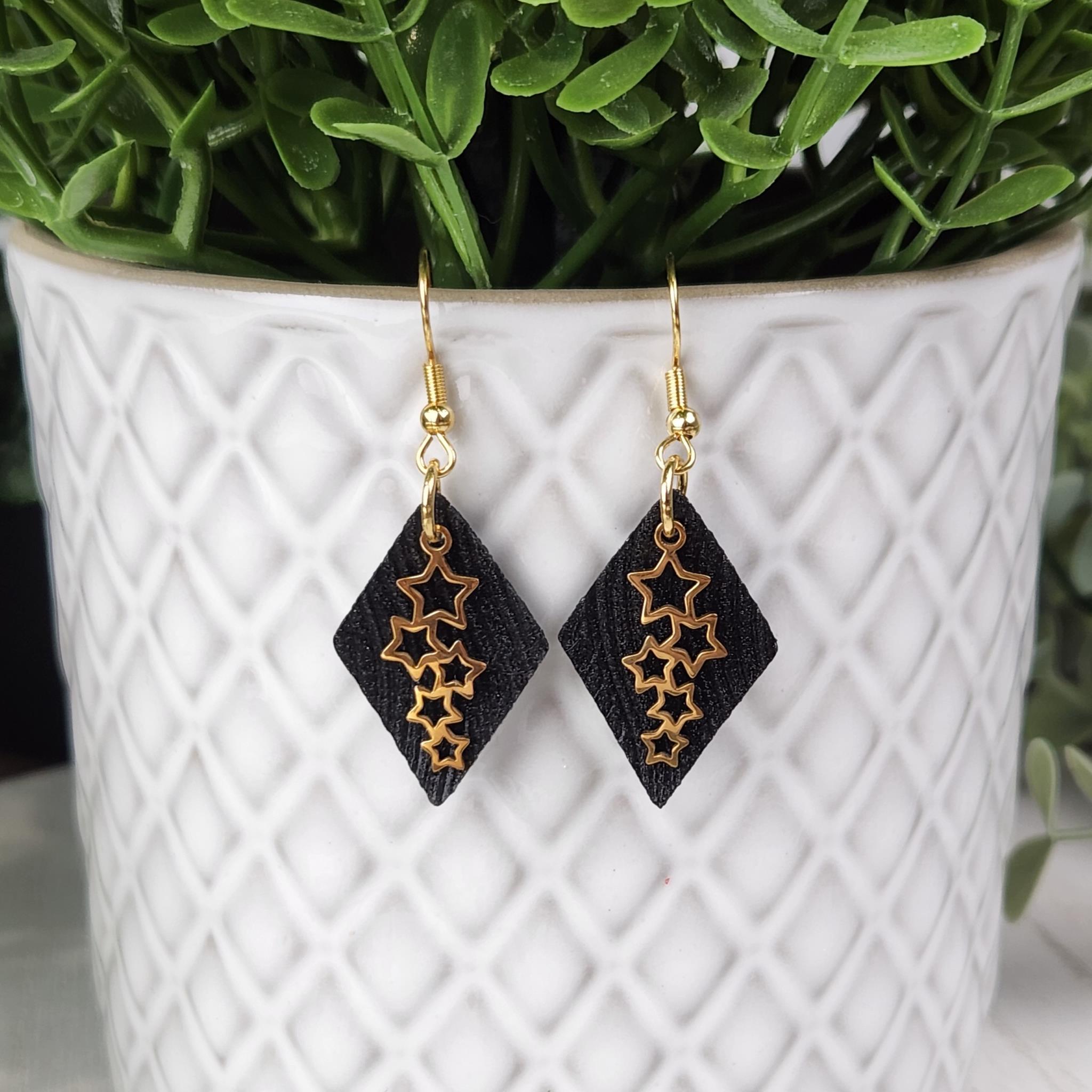 Glittery black faux leather with gold shooting stars.   Made with hypoallergenic hooks.